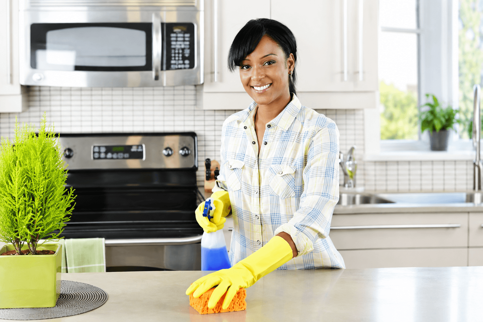 Caregiver smiling while cleaning a bright home kitchen
